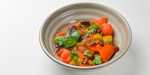 Baked vegetable salad in a cermaic bowl over white background. Delicious healthy autumn or winter salad.