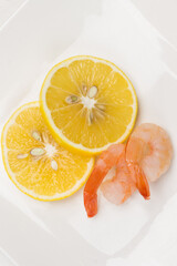 Shrimp and lemon wedges on white.