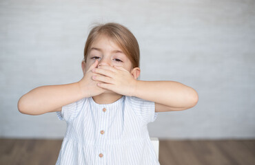Little girl closing her mouth with hands. Childhood trauma, traumatic experience. Psychological...