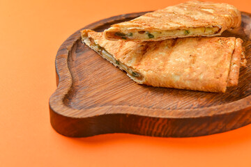 Lavash with suluguni cheese inside. Delicious snack. Served on a wooden board over orange background.