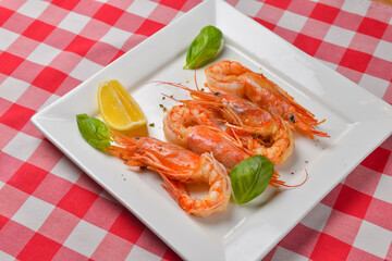 Fresh organic shrimp cocktail with mayonnaise salad. Served on a white plate over red plaid tablecloth.