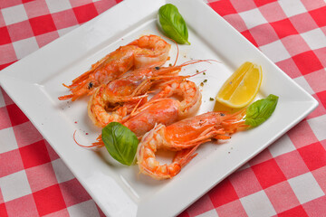 Fresh organic shrimp cocktail with mayonnaise salad. Served on a white plate over red plaid tablecloth.