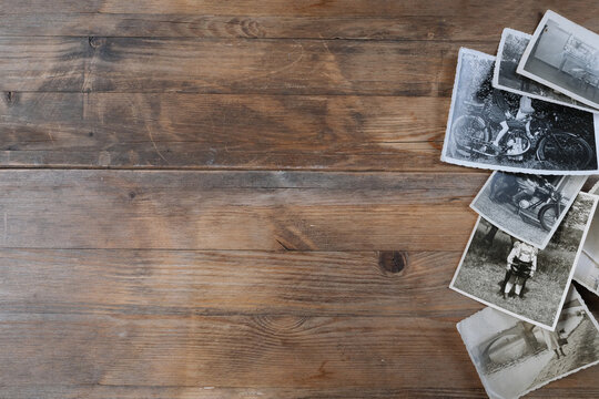stack of old vintage monochrome photographs on photographic paper on natural wood background, concept of genealogy, memory of ancestors, family tree, nostalgia, childhood, remembering