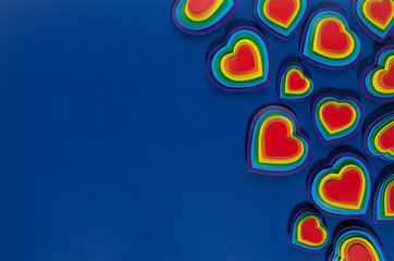Valentine lgbt festive background - rainbow bright hearts on dark blue backdrop as border, top view.