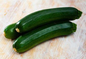 Closeup of fresh zucchini with chopped slices on wooden surface. Vegetarian food concept