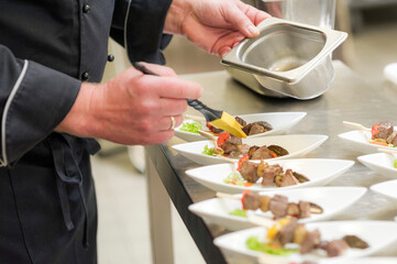 Catering Buffet Partyservice Essen zubereiten von einem Koch auf kleine Teller