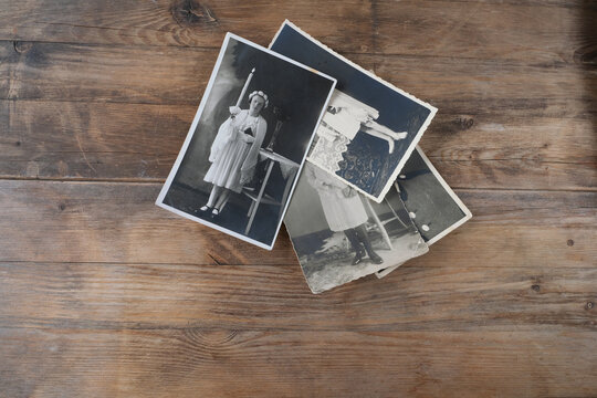 stack of old vintage monochrome photographs on photographic paper on natural wood background, concept of genealogy, the memory of ancestors, family tree