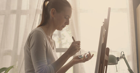 Artist painting on canvas with spatula