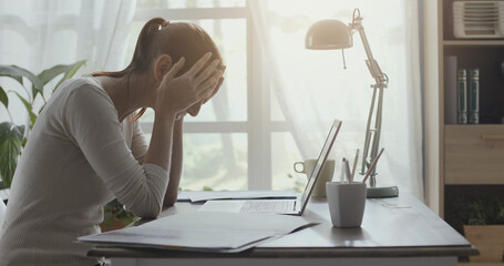 Exhausted woman with headache working in her office