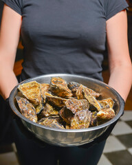 Fresh mussels in copper dish in hands. Waiter with a big bowl of mussels in a restaurant.