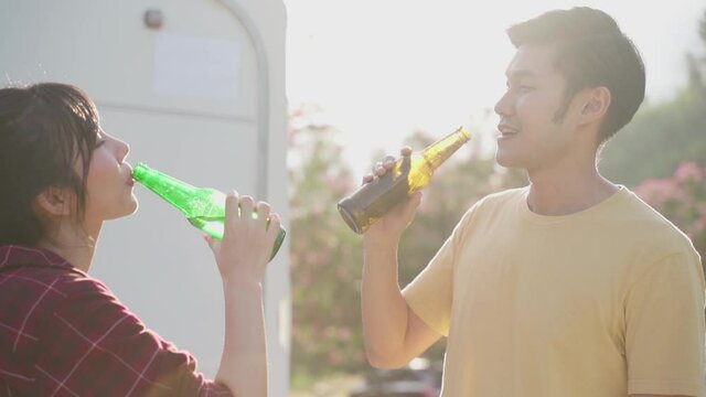 Young asian couple clinking and drinking beer together with happiness.