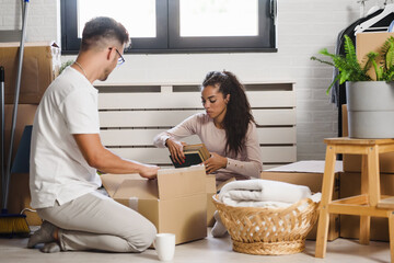 Happy multiethnic couple just moved into new empty apartment unpacking, cleaning, enjoying new home. Relocation. Moving in.