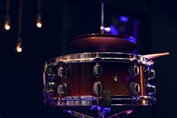 Snare drum and drumsticks close up in dark.