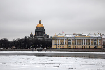 Beautiful and old buildings in the center of St. Petersburg. The embankment of the frozen river. Winter cloudy snowy day. Ancient architecture.
