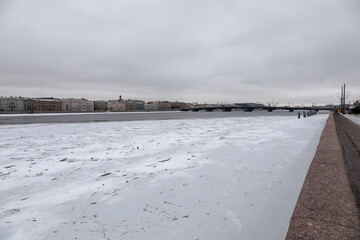 Beautiful and old buildings in the center of St. Petersburg. The embankment of the frozen river. Winter cloudy snowy day. Ancient architecture.
