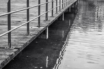 Obraz premium Railing of the walkway of a jetty over the water. Black and white.