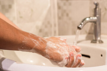 Close-up of man washing hands with soap over sink in bathroom. hygiene treatment