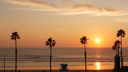Palms silhouette sunset sky, California aesthetic. Oceanside USA. Tropical pacific ocean beach atmosphere. Dark black palm tree, Los Angeles vibes. Lifeguard watchtower, baywatch watch tower hut.