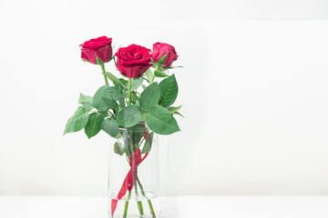 Bouquet of red roses in a glass bottle placed on a wooden table. Wedding decorations, Valentine's day, home decorations Or office. Doing export business of flowers. copy space