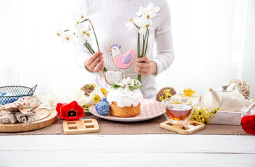 A woman decorates a festive table with flowers for the celebration of Easter.