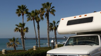 Motorhome trailer or caravan for road trip. Waterfront tropical palm trees and pacific ocean beach, Oceanside California USA. Beachfront vacations in camper van, RV motor home. Mobile home campervan.