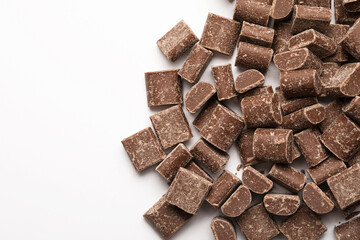 Chocolate chunks for hot chocolate preparation or dessert ingredients. Heap of cocoa milk chocolate morsels on white background, top view