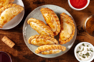 Empanadas, top shot with various sauces on a wooden table