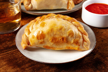 Empanada close-up with a red salsa and a glass of wine in the blurred background