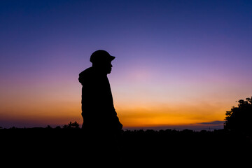 Fototapeta premium silhouette dark young man wearing a hat standing emotions with evening Twilight sky with cloud in the winter season at sunset Abstract background.Copy space for your