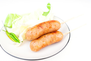 Thai style sausage, made from glass noodles, lean pork with garlic, pepper, coriander seed, seasoning sauce, grilled. placed on a plate with fresh cauliflower and chili. Thai street food