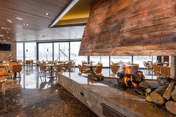 Interior of an empty mountain restaurant with large fireplace in the middle