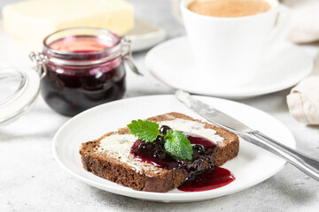 Bread with butter and blackcurrant jam. Rye bread sandwich with sunflower seeds with butter and jam. Breakfast