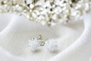 Fototapeta na wymiar elegant bride's earrings on white fabric on the background of a tiara. wedding accessories. close-up, macro
