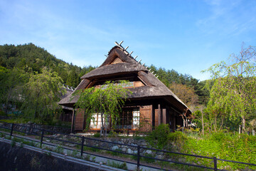 Traditional thatched roof buildings in the traditional village of Saiko Iyashi no Sato Nemba in Saiko, Yamanshi, Japan with Mount Fuji in the background.