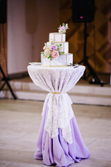 A classic tiered white and grey cake with flowers decoration and geometric pattern. A wedding cake.