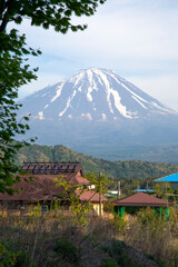 Traditional thatched roof buildings in the traditional village of Saiko Iyashi no Sato Nemba in Saiko, Yamanshi, Japan with Mount Fuji in the background.
