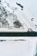 Two lane asphalt road in snowy winter morning from drone pov