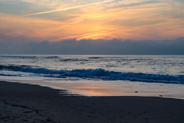 Fototapeta na wymiar Cloudy sunset over the ocean and a little beach