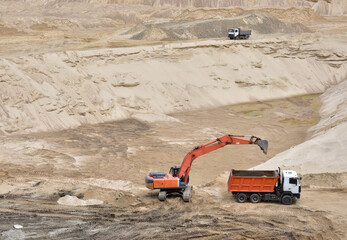 Excavator load the sand into dump truck in open-pit mining. Developing the sand in the opencast,...