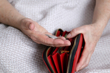 Elderly woman takes out a coins from her wallet, wrinkled female hands closeup. Concept of poverty, pension payments, pensioner with metal money