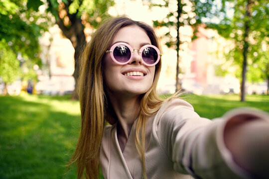Cheerful woman in sunglasses outdoors in the park Green grass fresh air