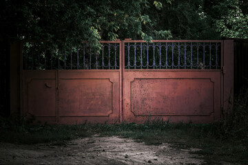 Horror concept. Iron scary rusty old closed metal gates with mystical shadows in a dark forest...