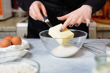 the cook puts a piece of butter in a bowl with sugar