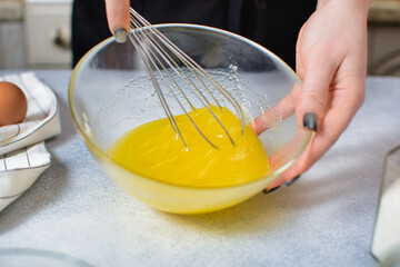 the cook whips the egg-oil mixture with a whisk to prepare the dough