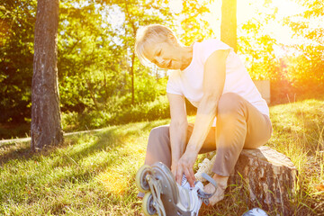 Seniorin beim Anziehen von Rollerskates im Park