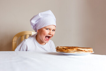 Photo shoot baby in white chef cap with pancakes on white background . Carnival Festival