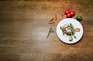Salad with goat cheese, tomatoes, baguette on a white plate. Place for text