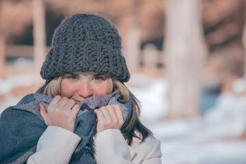 Winter horizontal portrait of smiling beautiful blonde girl in a snow day with a gray hat and long scarf. Closeup beauty photo. Winter outdoor 2021.