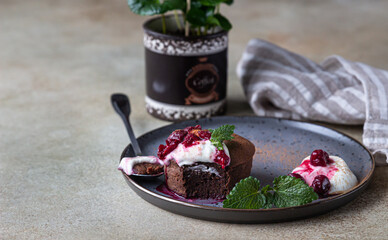 Mini chocolate cake or brownie with cream, cherry and mint on a ceramic plate. Chocolate fondant.
