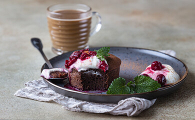 Mini chocolate cake or brownie with cream, cherry and mint on a ceramic plate and cup of coffee. Chocolate fondant. Breakfast or dessert for Woman or Mother Day.